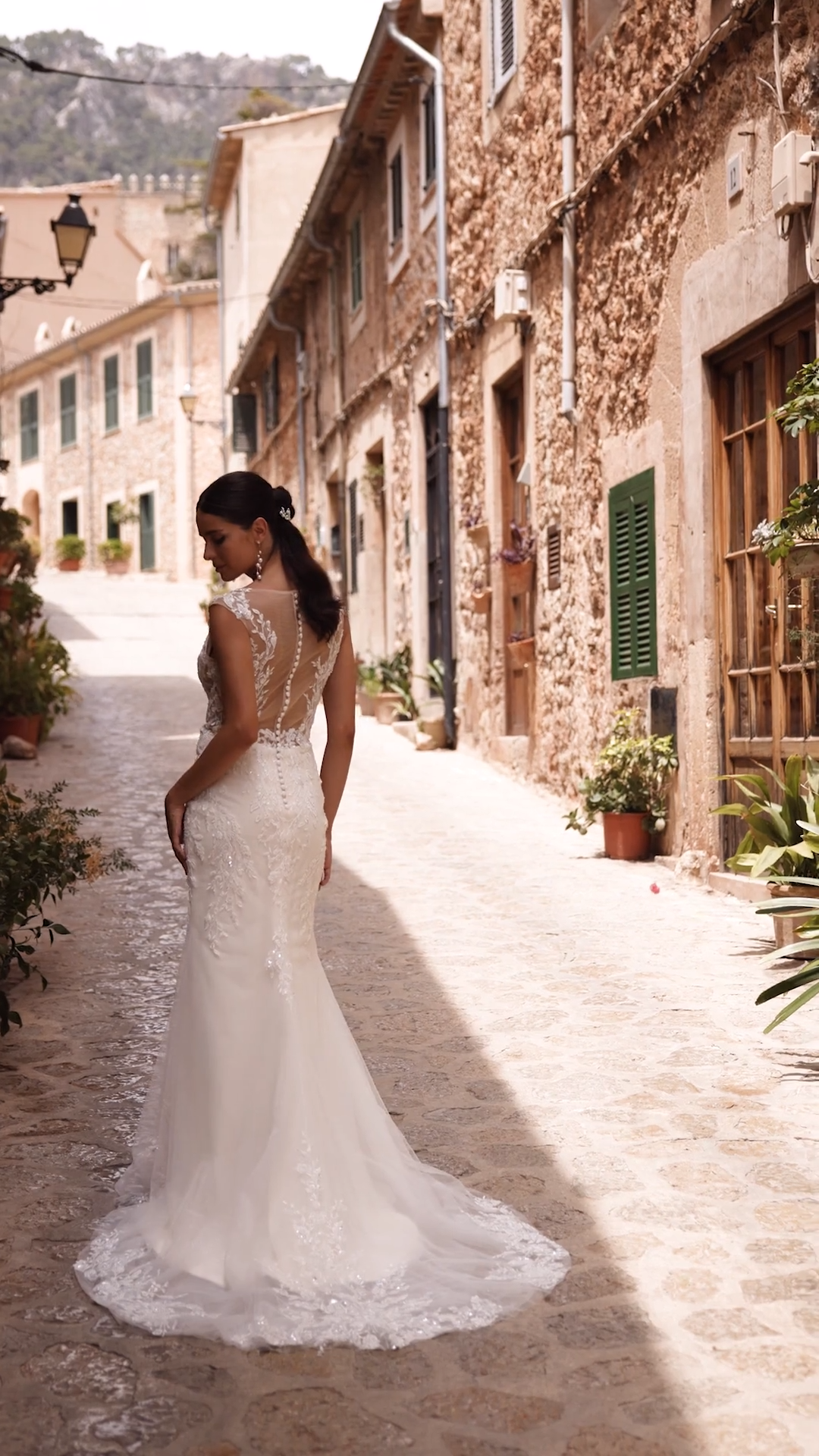 Bride wearing a sparkly lace wedding dress with cap sleeves and illusion back with crystal buttons Bride wearing a sparkly lace wedding dress with cap sleeves and illusion back with crystal buttons