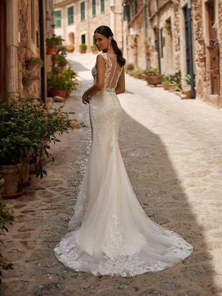Bride looking over shoulder in a mermaid wedding dress with illusion bateau back and sweep train Bride looking over shoulder in a mermaid wedding dress with illusion bateau back and sweep train